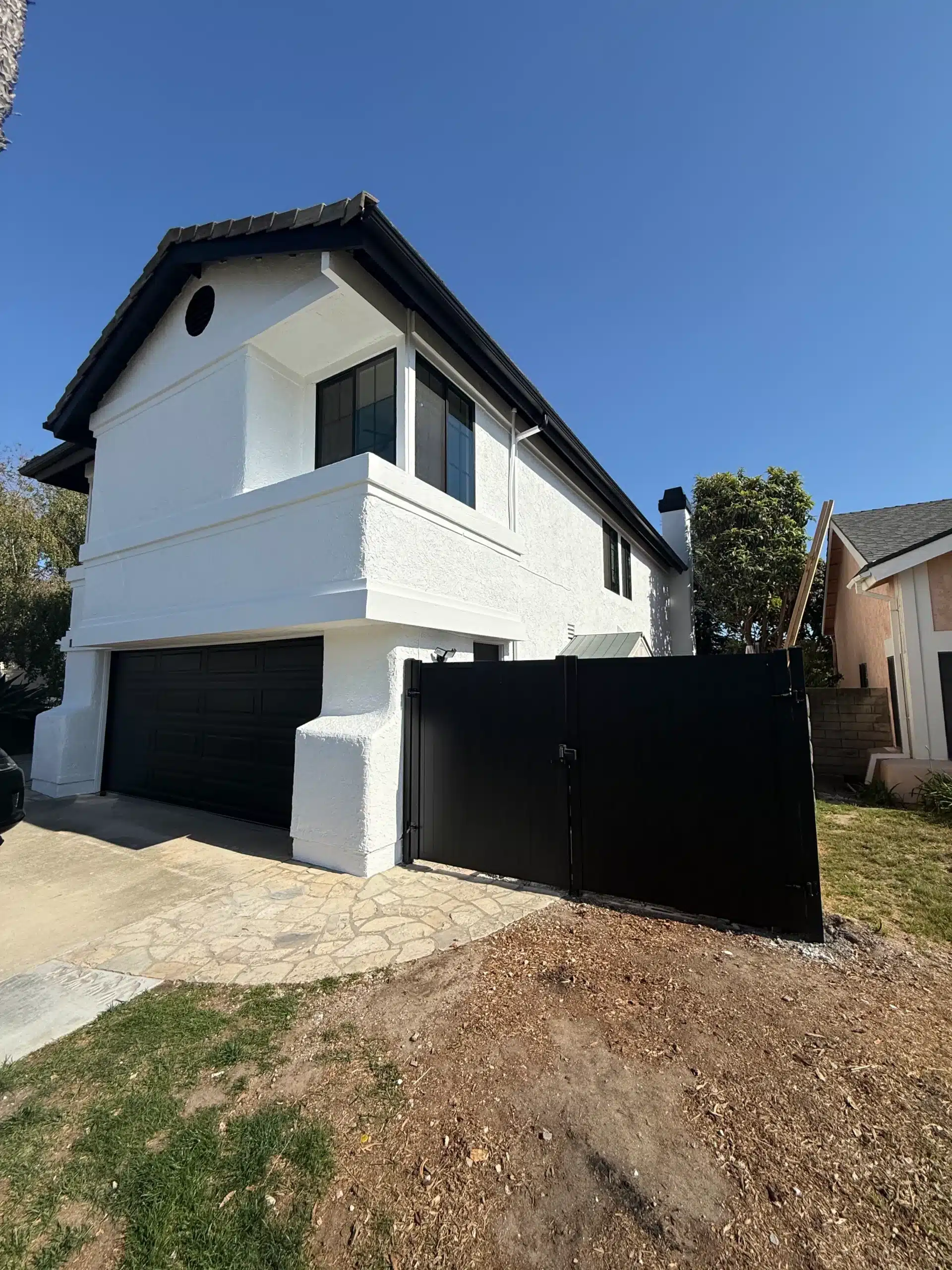 Residential Exterior Painting and Fence Services in Simi Valley California Side view of a modern white house with dark garage door and fence, completed by exterior painting in Simi Valley California.