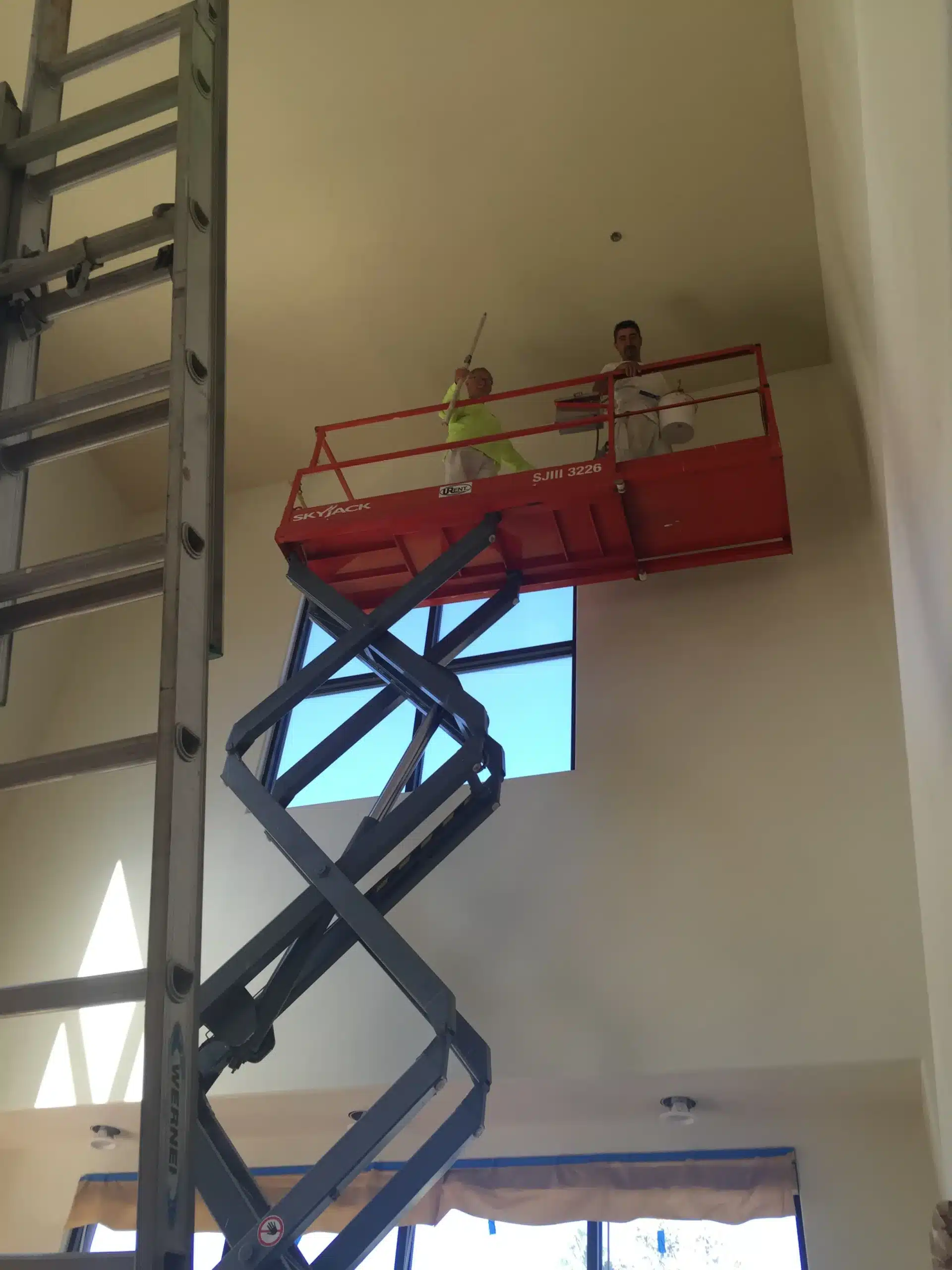High Ceiling Painting Services Simi Valley California Two painters on a scissor lift painting a high commercial ceiling in Simi Valley California.