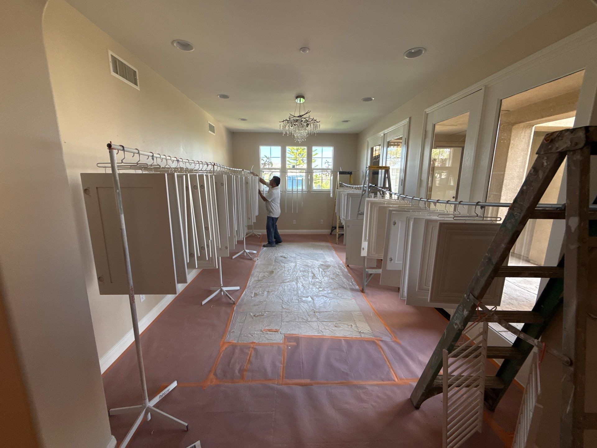 Interior Hallway Painting In Progress Cream-colored interior hallway with white trim, recessed lighting, and protective coverings during residential painting