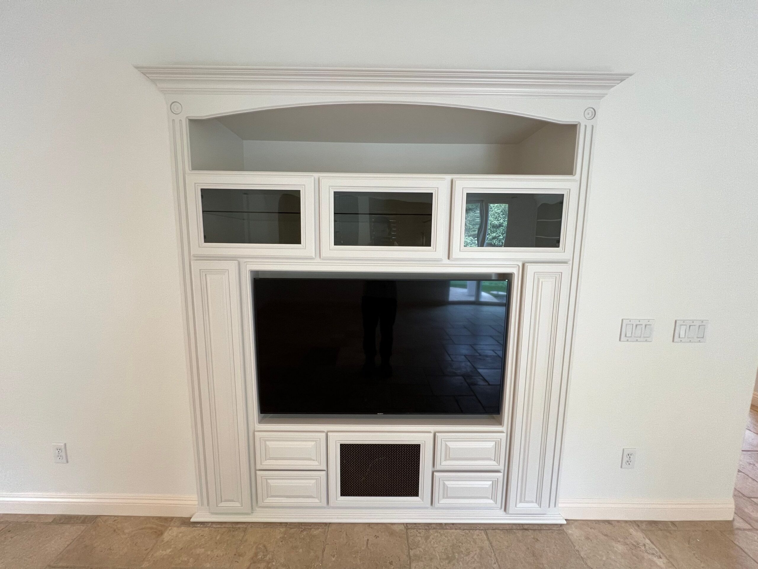 Cream Built-in Entertainment Center Cream-painted built-in entertainment center with white trim, glass-door upper cabinets, and flat-screen TV mounted in