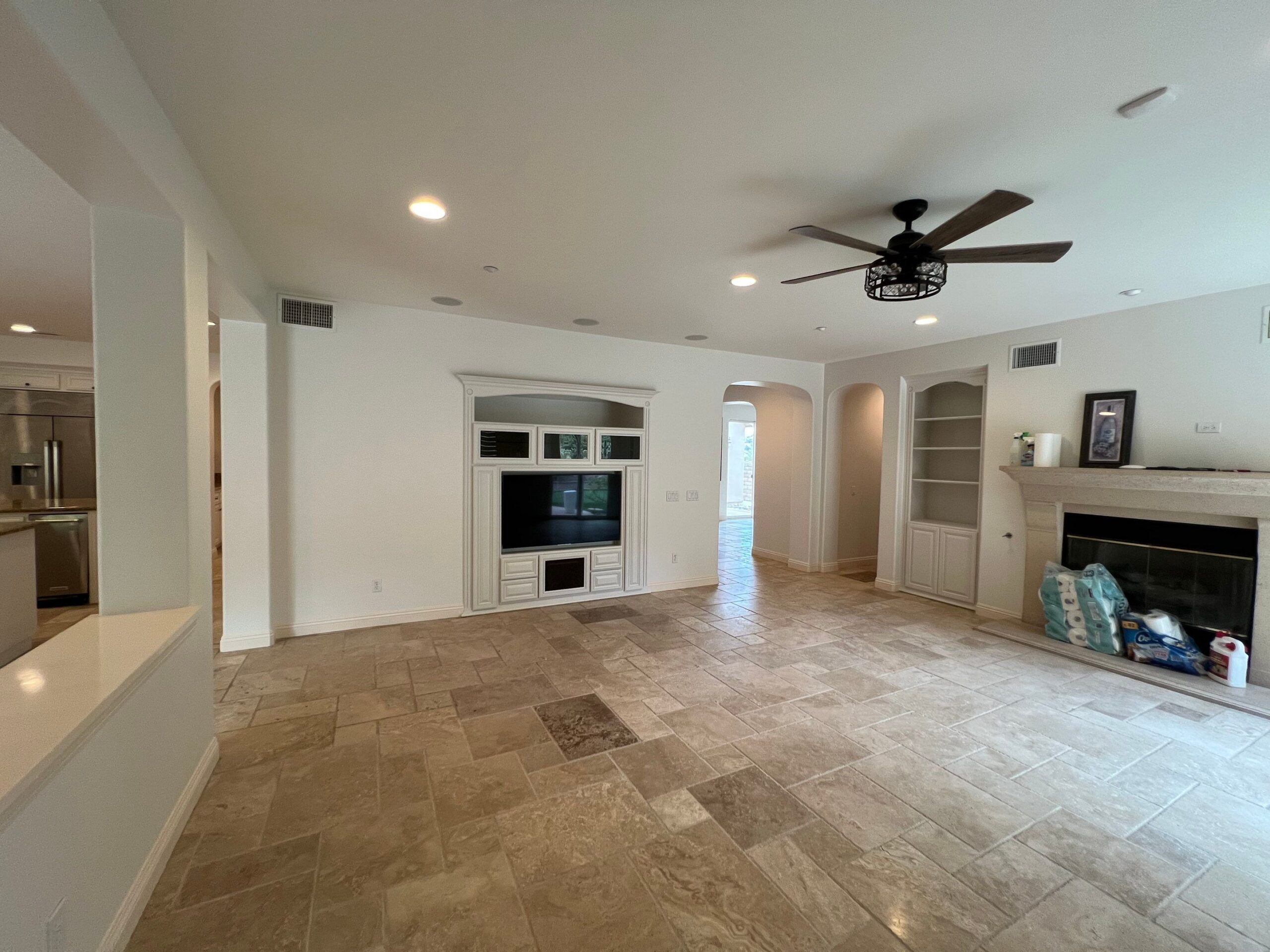 Cream Interior Living Room Cream-painted interior living room with travertine tile flooring, recessed lighting, black ceiling fan, and white