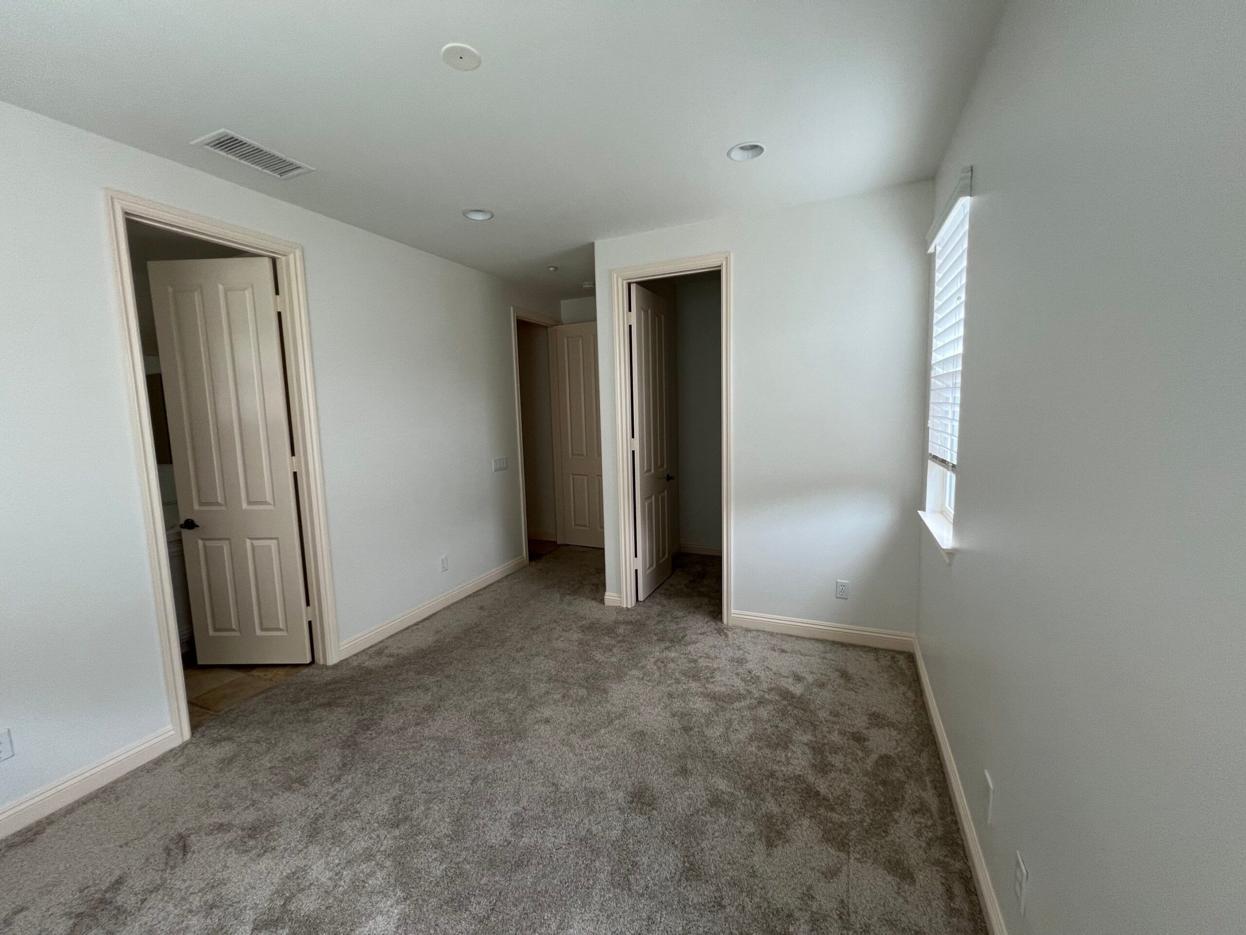 Cream Interior Bedroom Painting Cream-painted interior bedroom with white trim, beige carpet, recessed ceiling lights, and multiple doorways in residential