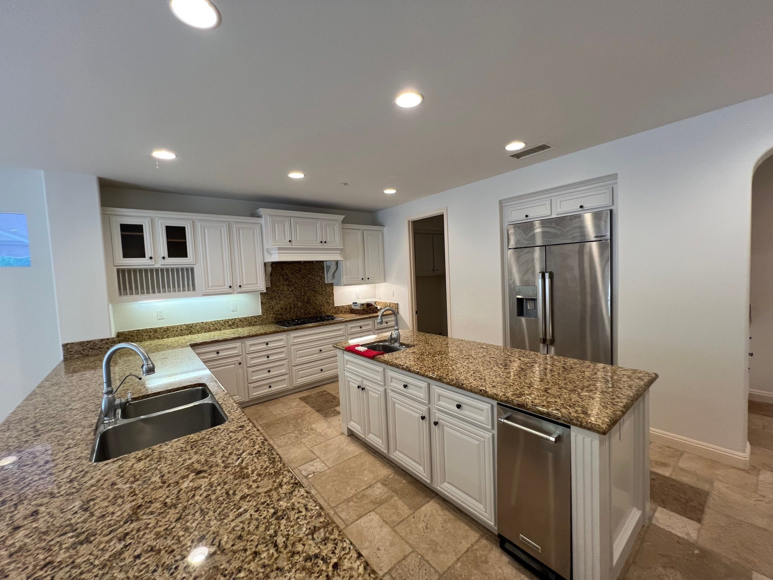 Cream Kitchen Cabinetry With Granite Cream-painted kitchen cabinets with speckled granite countertops, stainless steel appliances, and recessed ceiling lighting